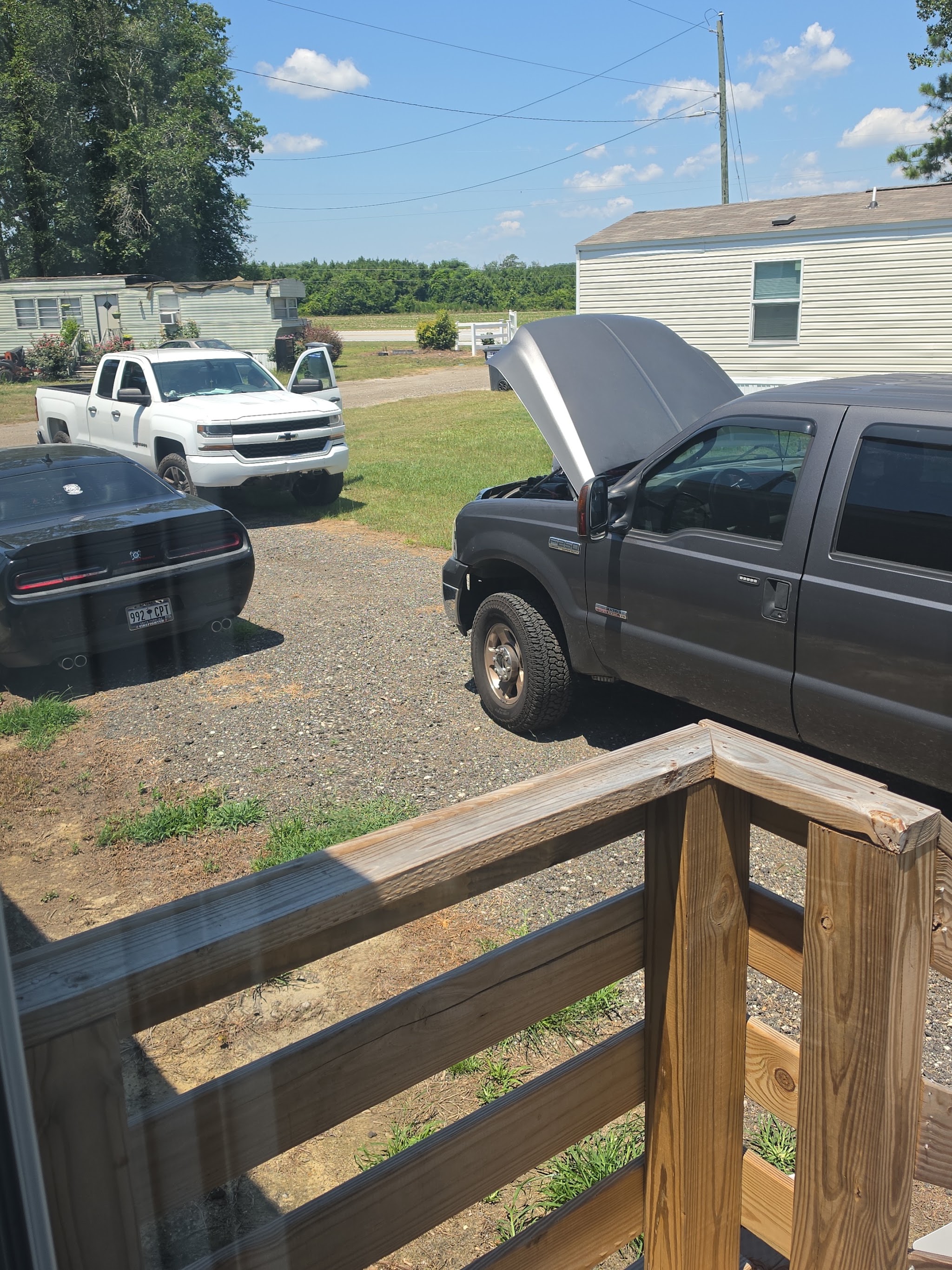 A pickup truck with its hood up in a driveway, being worked on